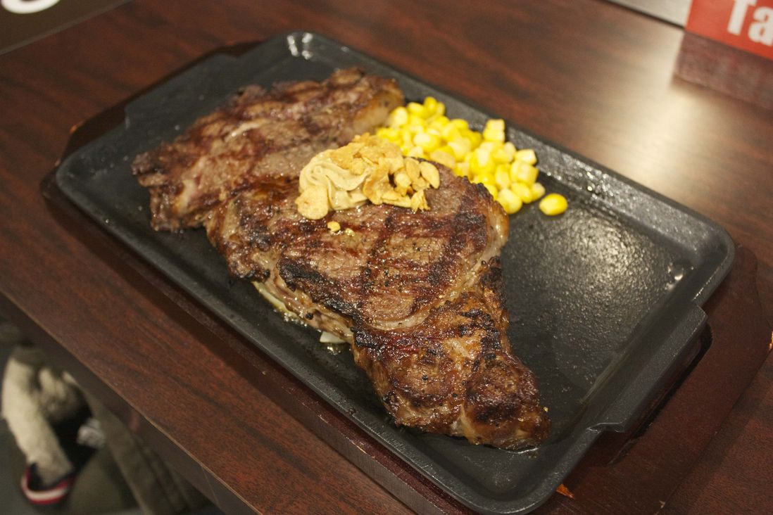 Steaks are served with corn and onions<br>